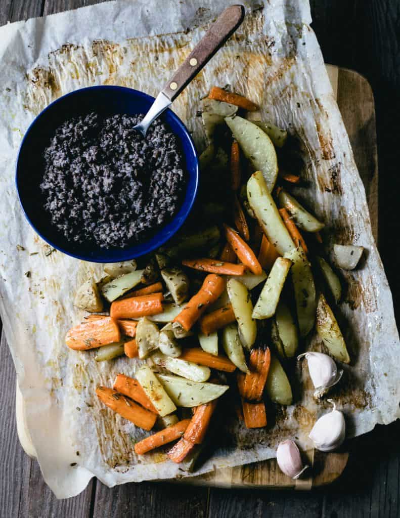 Oven roasted root vegetables and black lentils on a cutting board
