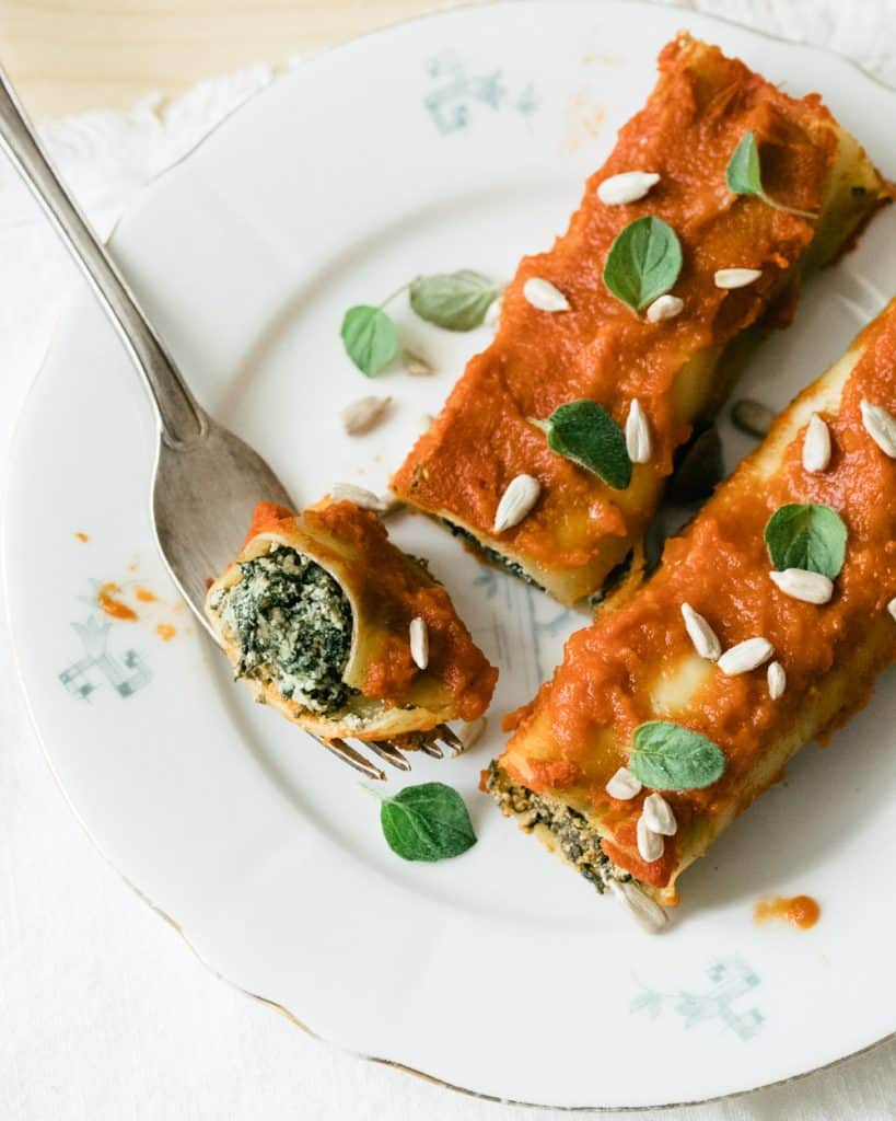 Two cannelloni on a plate with tomato sauce.
