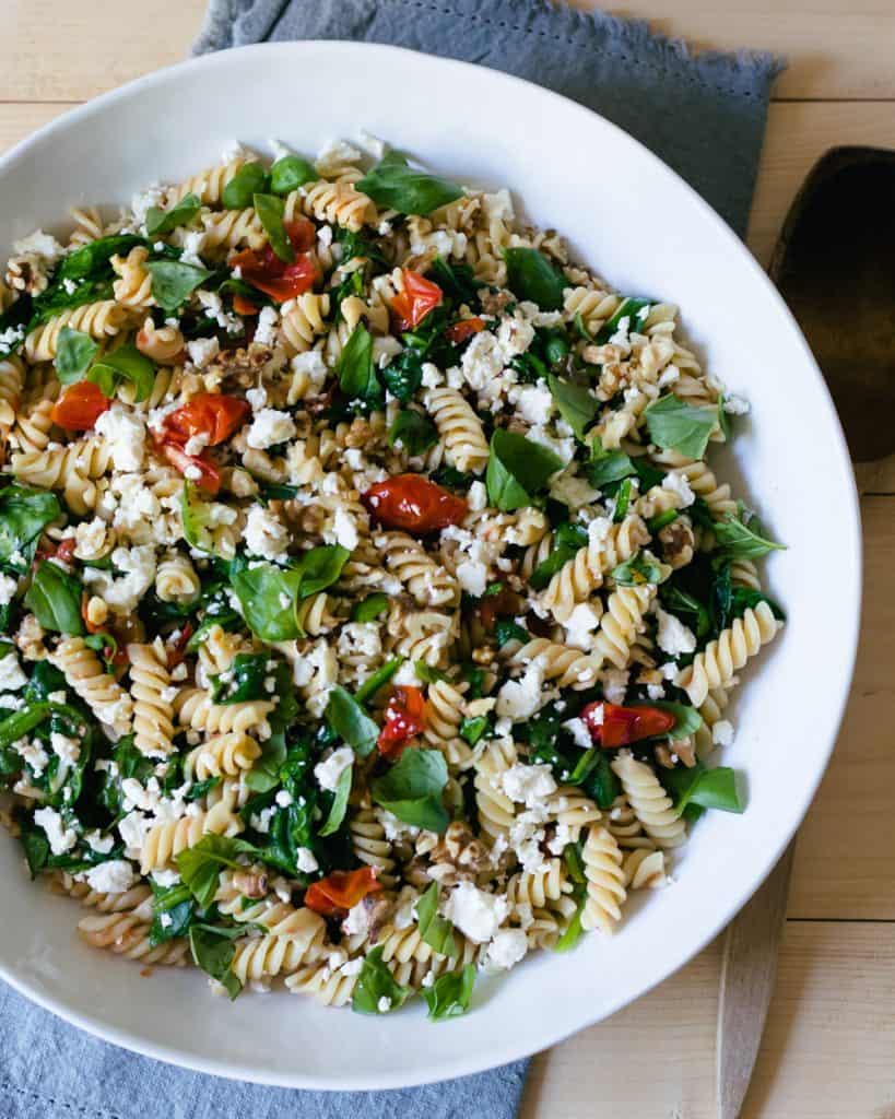 pasta in a bowl with spinach and tomatoes